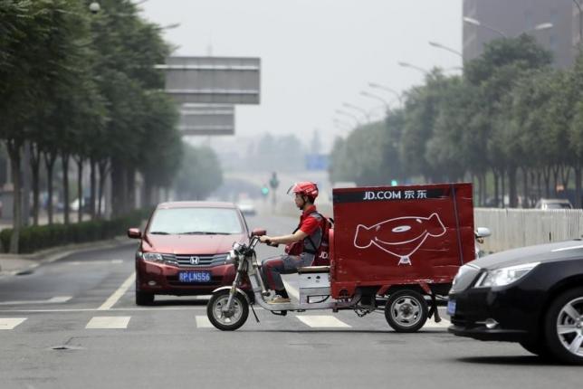 Liu, CEO and founder of China's e-commerce company JD.com, crosses a street on an electric tricycle during a delivery run in Beijing